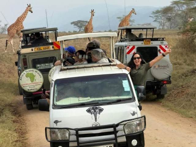 ELMAG SAFARIS pop-top safari van on a Kenyan game drive with giraffes beside the track